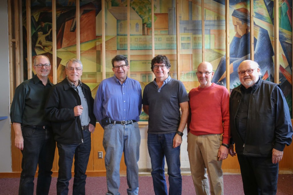 Six men standing in front of a painting
